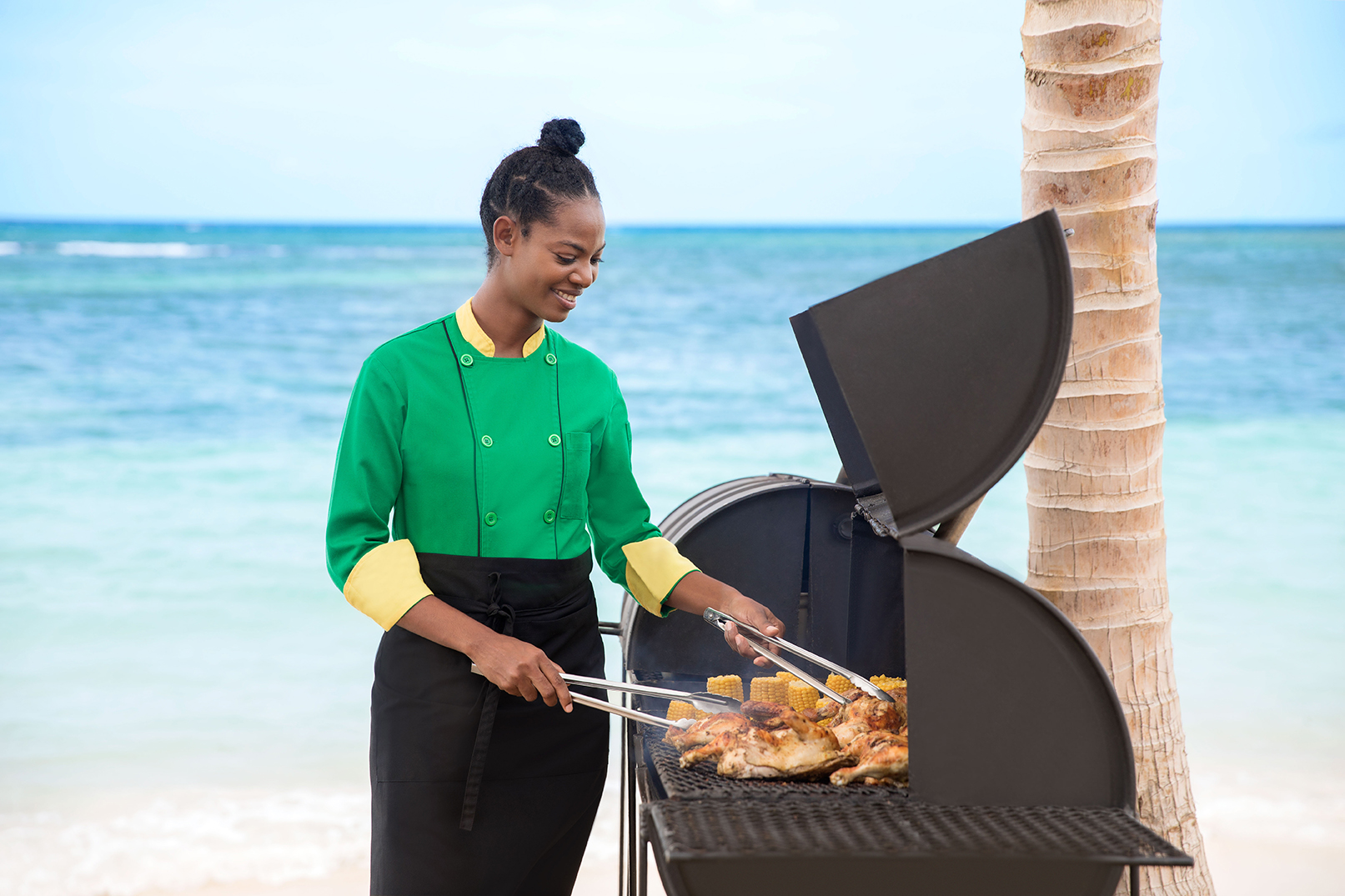 Jamaican woman cooking Jerk Chicken on the grill by the beach