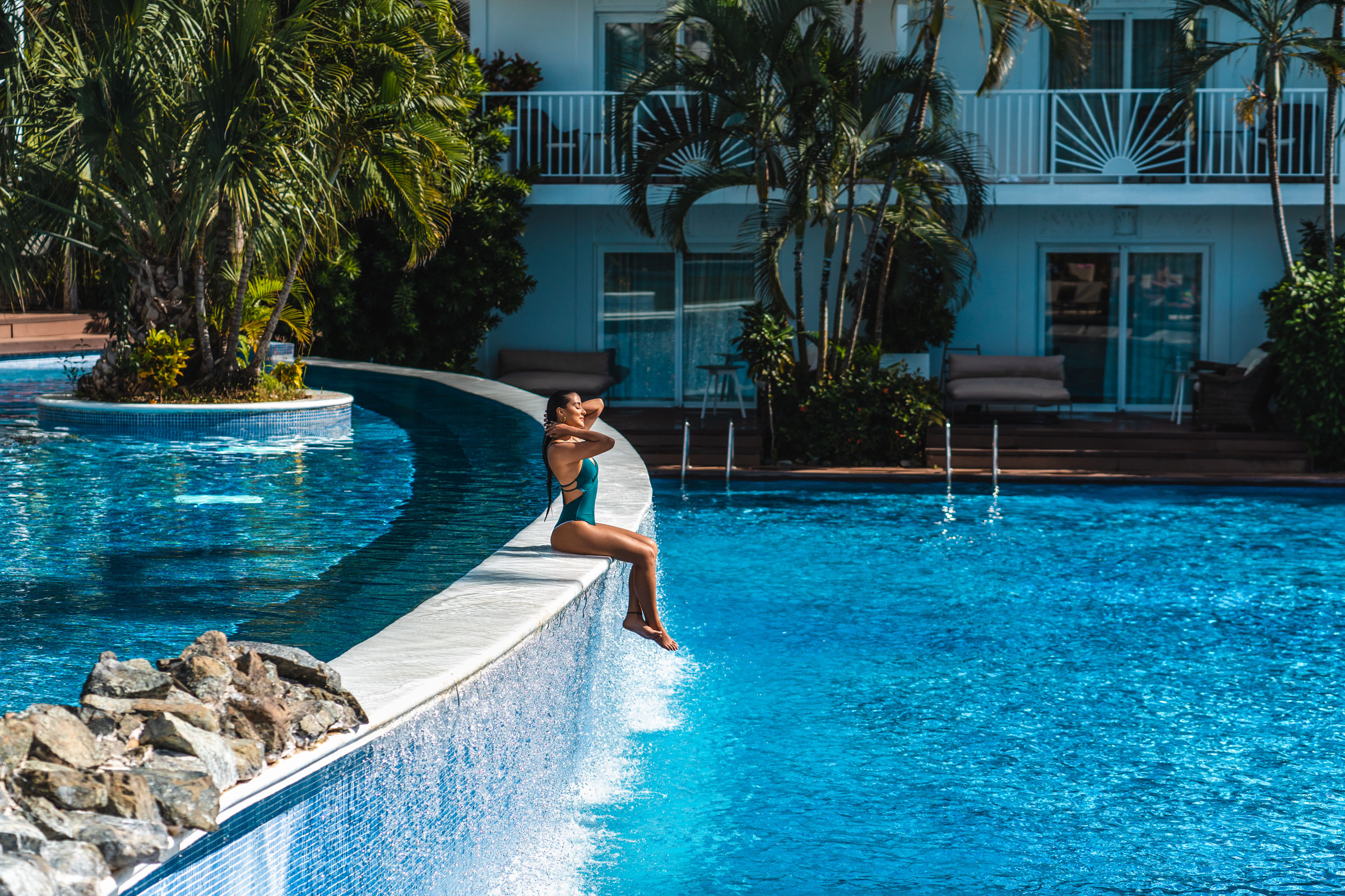 Woman sitting by a pool enjoying the cheapest time to visit a Caribbean resort